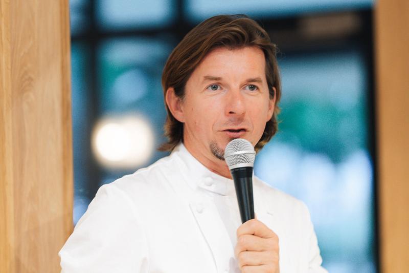 Fotografia eventowa z kolacji degustacyjnej w Szczecinie — Karol Okraza prezentuje dania gościom.