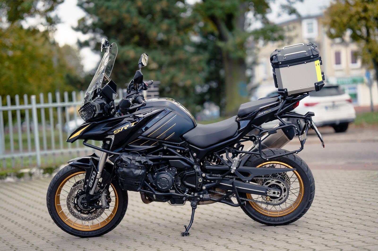 Czarny motocykl turystyczny z kufrem zaparkowany na chodniku