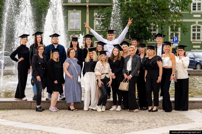 Reportaż z absolutorium w Szczecinie — grupa absolwentów z dyplomami przed fontanną w Parku Kasprowicza.