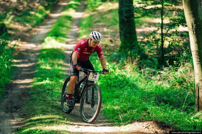 Fotografia sportowa z wyścigów MTB w Szczecinie — zawodnik pokonujący trasę w lesie.