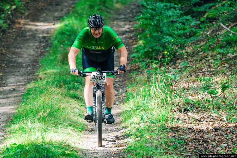 Fotografia sportowa z wyścigów MTB w Szczecinie — zawodnik pokonujący trasę w lesie.