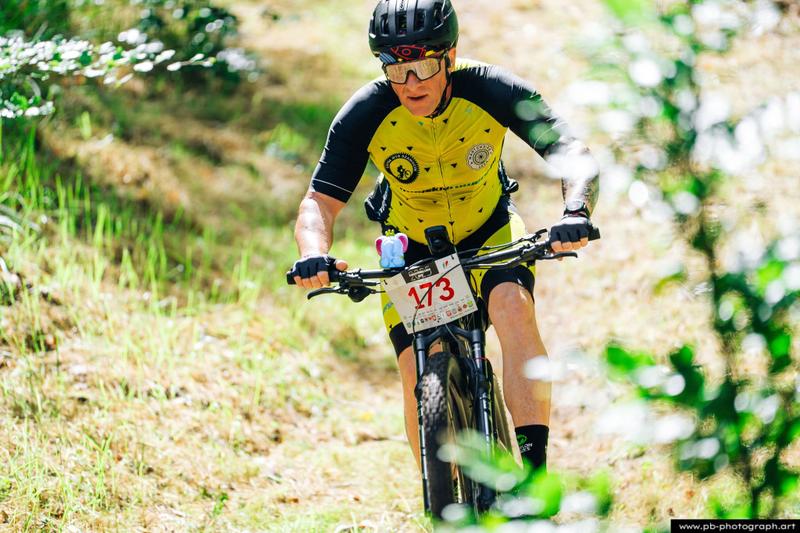 Fotografia sportowa z wyścigów MTB w Szczecinie — kolarz pokonujący trasę w lesie.