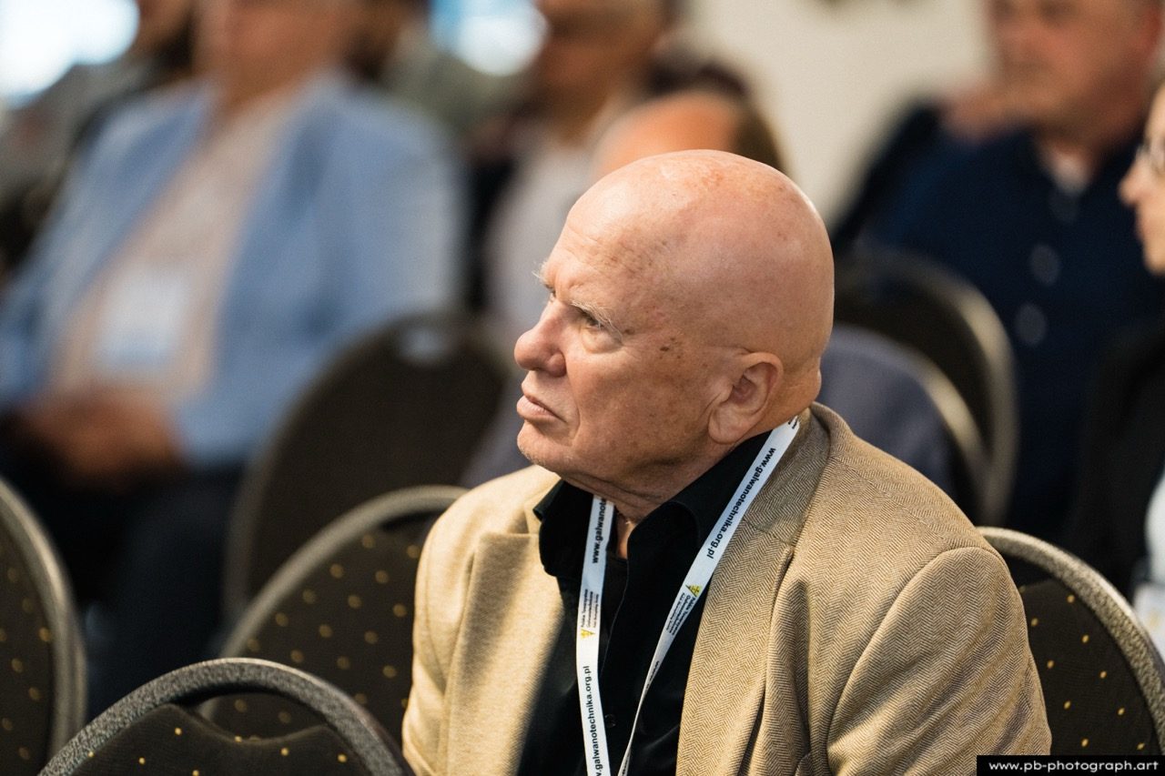 Mężczyzna w beżowej marynarce na konferencji.