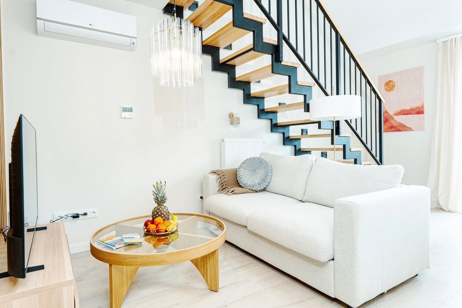 Salon z jasną sofą, stolikiem i schodami w apartamencie